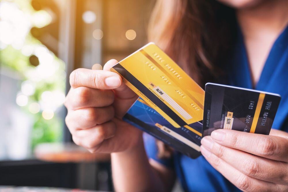 Woman holding three bank cards and selecting the correct one.