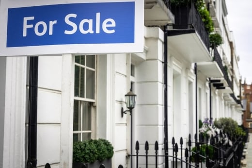Estate agent for sale sign outside a white terraced house in the uk