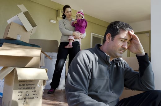 Man stressed while packing with woman behind him holding a small child